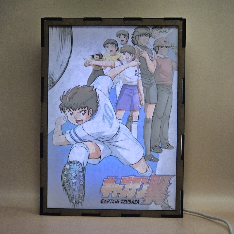 Lámpara ánime/manga  Supercampeones  con doble imagen del grupo Oliver Atom, Mark Lenders, Benji Price, Julian Ross, Tom Baker, Bruce Harper y Patty, vista encendida, con luz ambiente, donde se revela la ilustración completa al encender la luz LED.