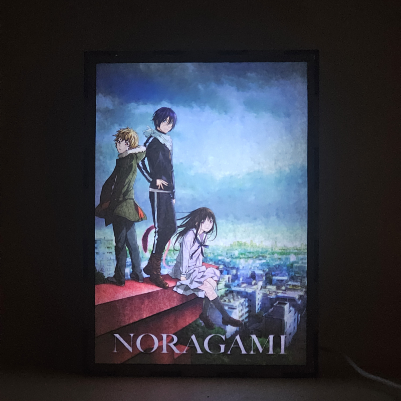 Lámpara ánime/manga  Noragami  con doble imagen del grupo Yato, Hiyori Iki y Yukine, vista encendida, donde se revela la ilustración completa al encender la luz LED.