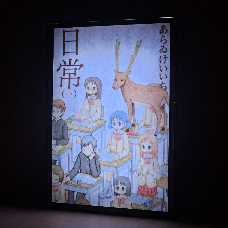 Lámpara ánime/manga  Nichijou  con doble imagen del grupo Yuuko Aioi, Sakamoto, Mai Minakami, Nano Shinonome, Mio Naganohara y Koujirou Sasahara, vista encendida, donde se revela la ilustración completa al encender la luz LED.