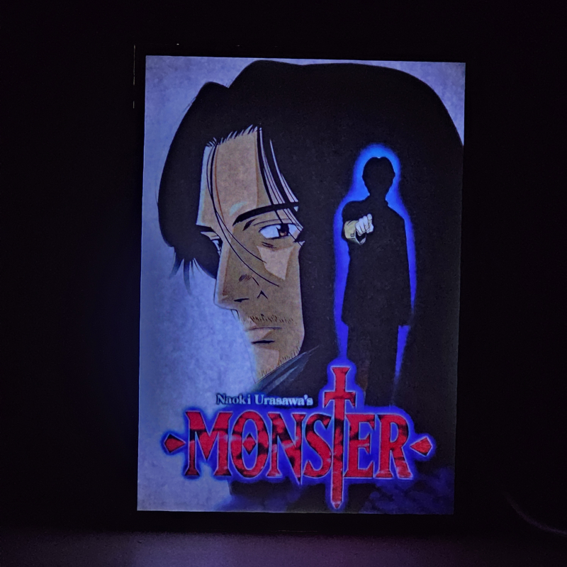Lámpara ánime/manga  Monster  con doble imagen de la pareja Kenzo Tenma y Johan Liebert, vista encendida, donde se revela la ilustración completa al encender la luz LED.