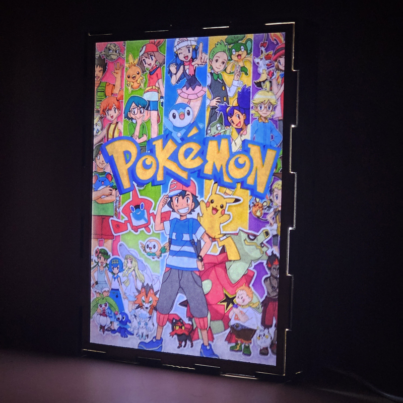 Lámpara ánime/manga  Pokémon  con doble imagen del grupo Ash Ketchum, Pikachu, Misty, Brock, Maya, Aura, Lem, Serena, Iris y Millo, vista encendida, donde se revela la ilustración completa al encender la luz LED.