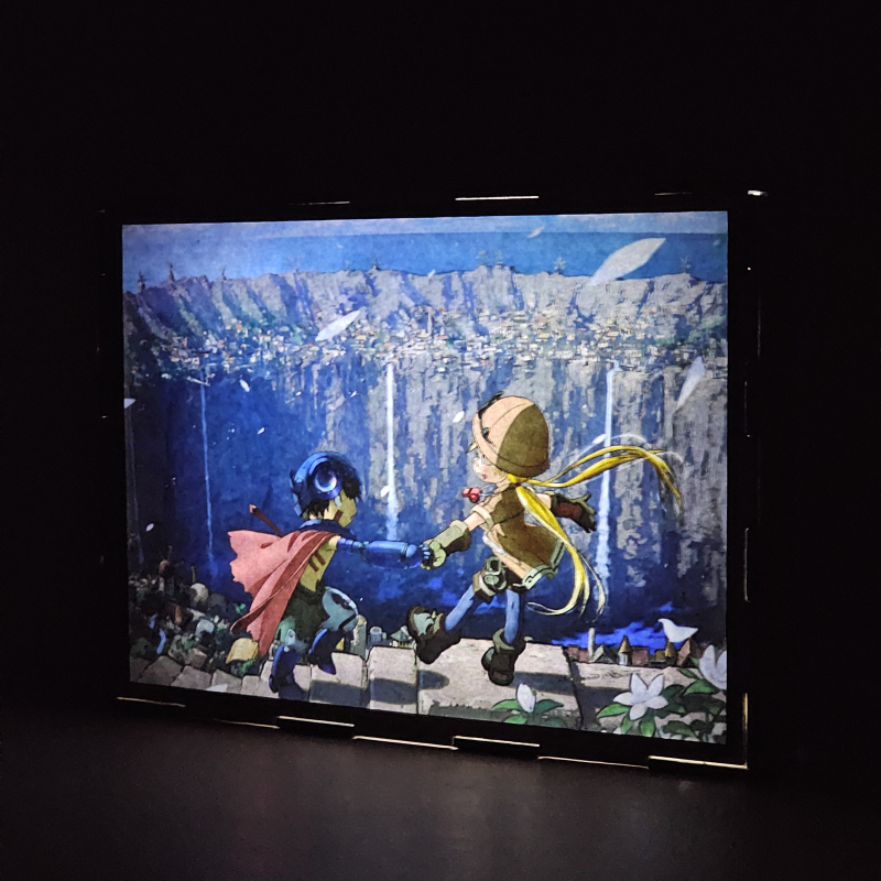 Lámpara ánime/manga  Made in Abyss  con doble imagen de la pareja Riko y Reg, vista encendida, donde se revela la ilustración completa al encender la luz LED.