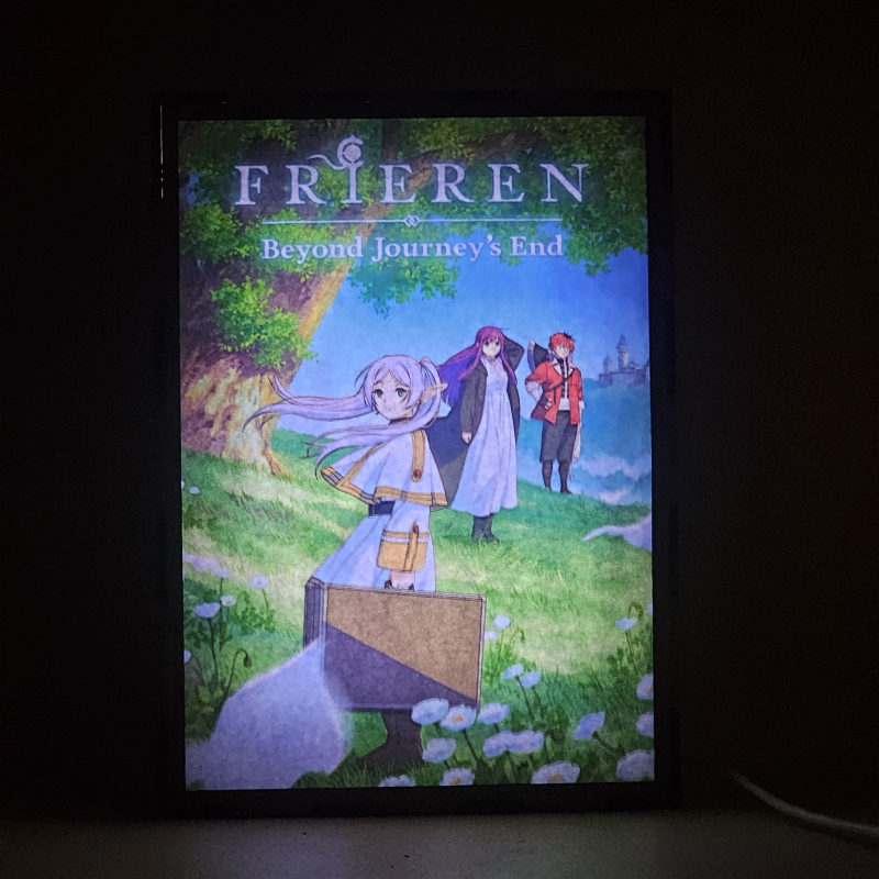 Lámpara ánime/manga  Frieren  con doble imagen del grupo Frieren, Fern y Stark, vista encendida, donde se revela la ilustración completa al encender la luz LED.