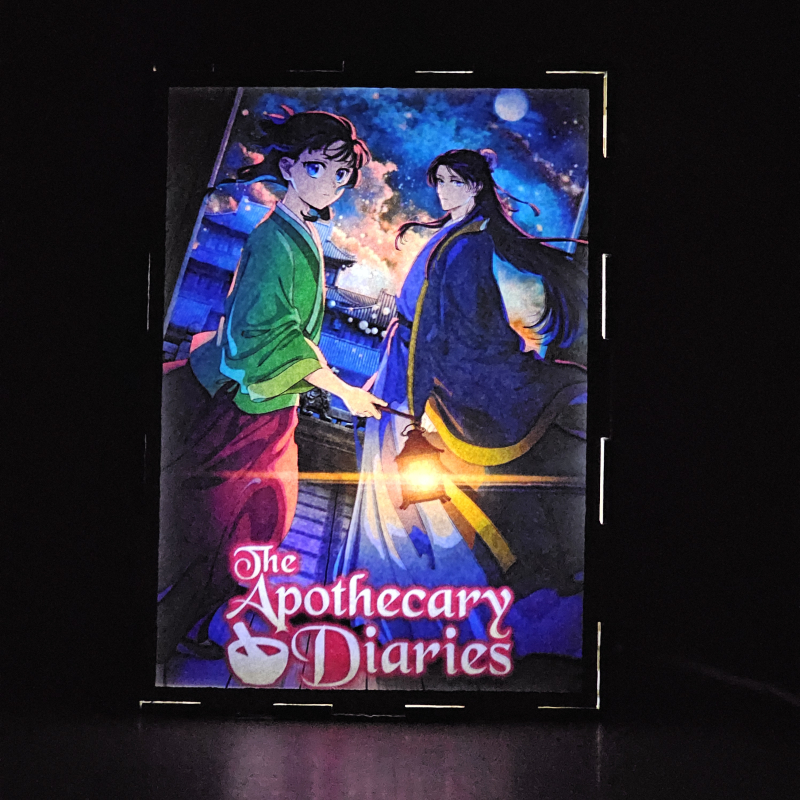 Lámpara ánime/manga  Los Diarios de la Boticaria  con doble imagen de la pareja Maomao y Jinshi, vista encendida, donde se revela la ilustración completa al encender la luz LED.