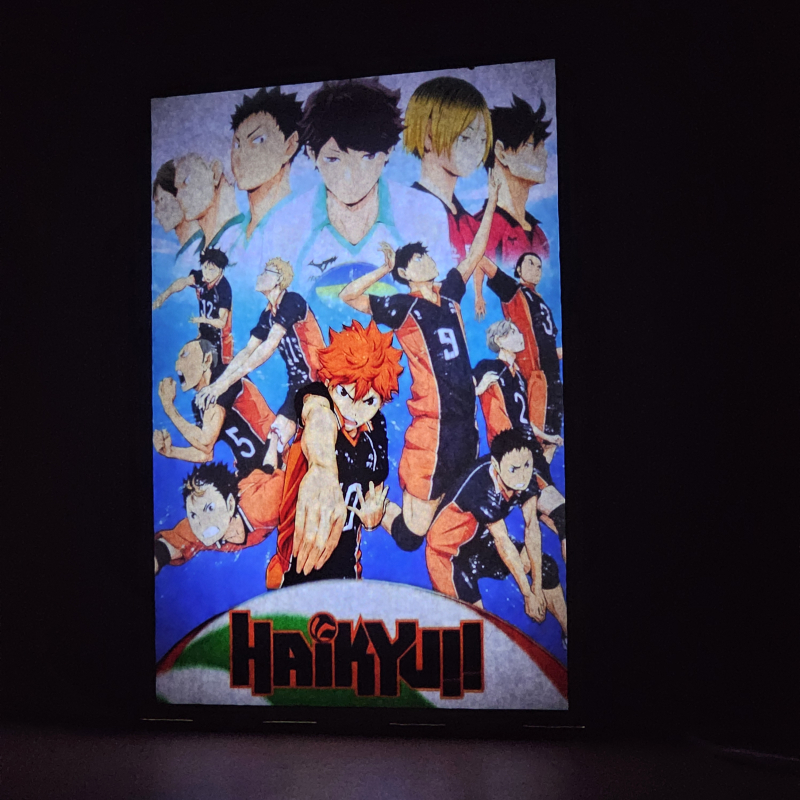 Lámpara ánime/manga  Haikyuu  con doble imagen del grupo Shoyo Hinata, Tobio Kageyama, Kei Tsukishima, Tadashi Yamaguchi, Kenma Kozume, Kuroo Tetsurō, Ryunosuke Tanaka, Yuu Nishinoya, Daichi Sawamura, Koushi Sugawara y Asahi Azumane, vista encendida, donde se revela la ilustración completa al encender la luz LED.