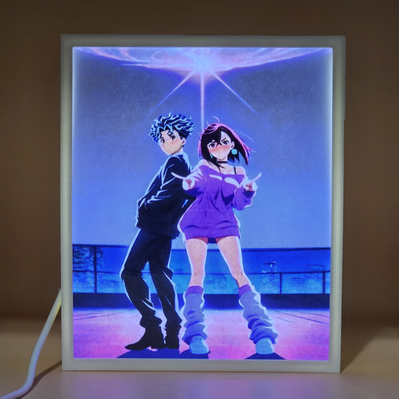 Lámpara ánime/manga  DAN DA DAN  con doble imagen de la pareja Okarun y Momo Ayase, vista encendida, donde se revela la ilustración completa al encender la luz LED.
