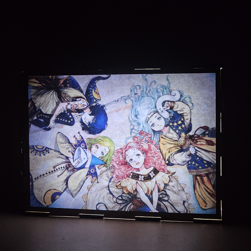 Lámpara ánime/manga  Witch Hat Atelier  con doble imagen del grupo Coco, Agott, Tetia y Richeh, vista encendida, donde se revela la ilustración completa al encender la luz LED.