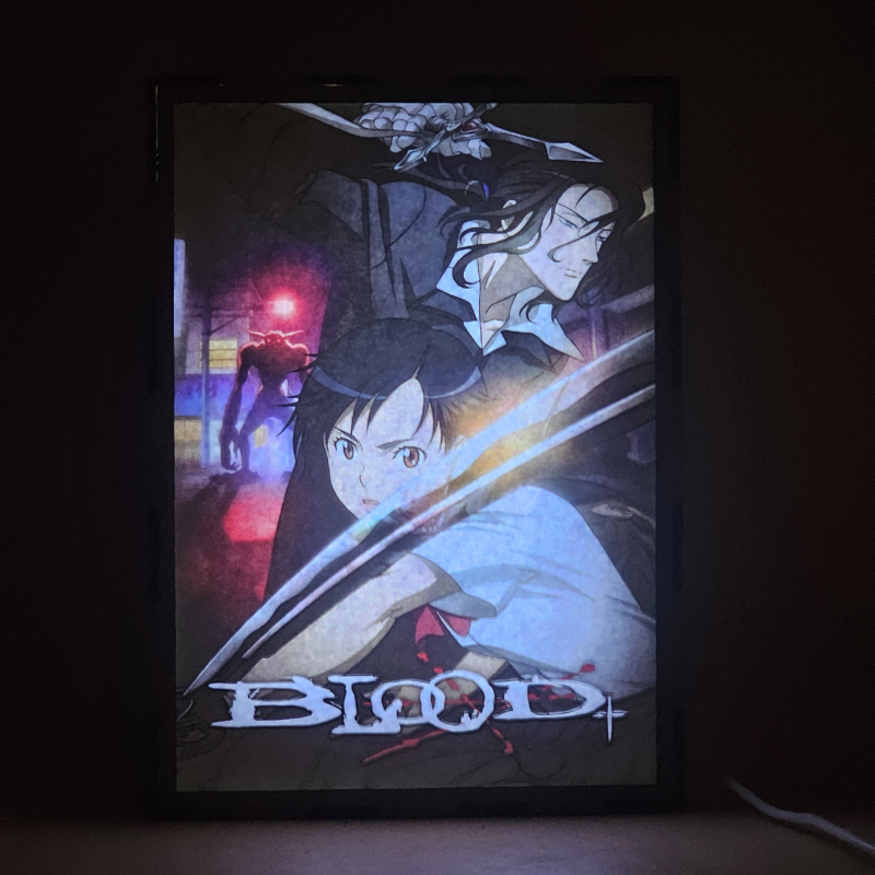 Lámpara ánime/manga  Blood+  con doble imagen de la pareja Saya Otonashi y Hagi, vista encendida, donde se revela la ilustración completa al encender la luz LED.