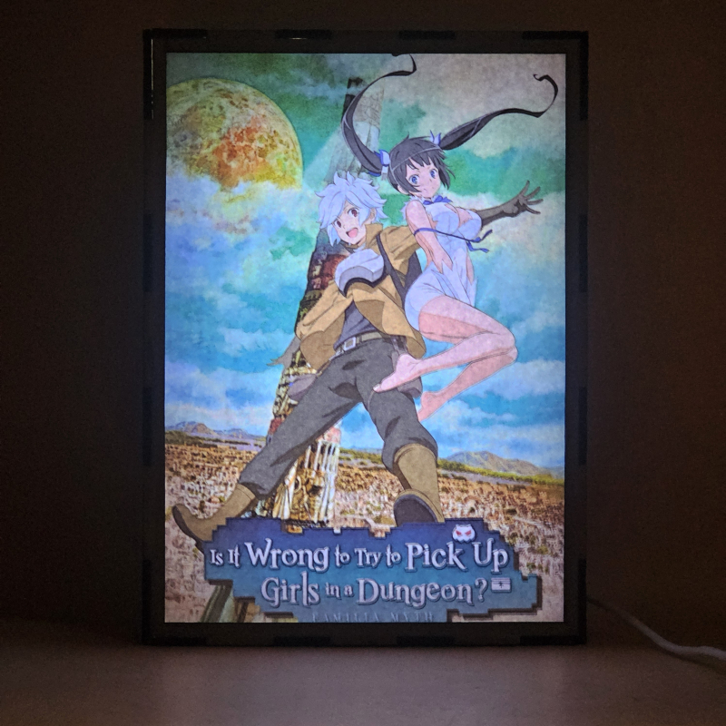 Lámpara ánime/manga  DanMachi  con doble imagen de la pareja Bell Cranel y Hestia, vista encendida, donde se revela la ilustración completa al encender la luz LED.