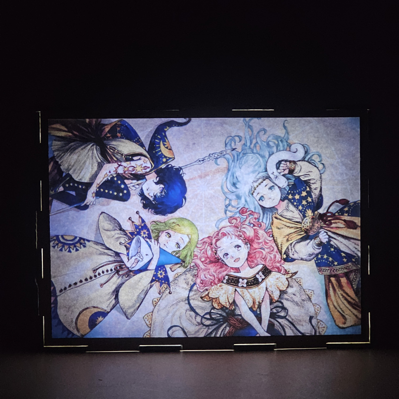 Lámpara ánime/manga  Witch Hat Atelier  con doble imagen del grupo Coco, Agott, Tetia y Richeh, vista encendida, donde se revela la ilustración completa al encender la luz LED.