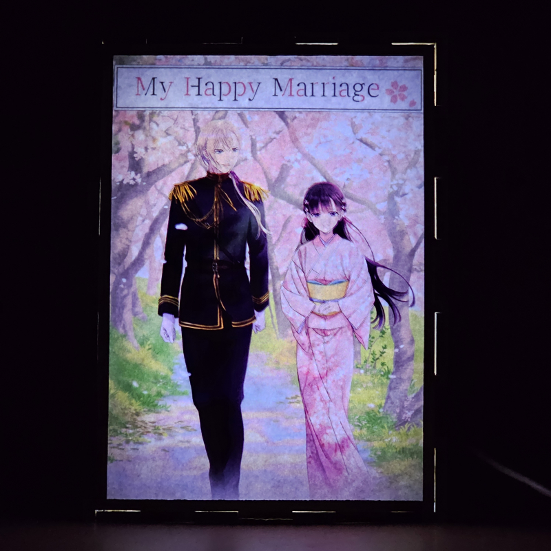 Lámpara ánime/manga  My Happy Marriage  con doble imagen de la pareja Miyo Saimori y Kiyoka Kudou, vista encendida, donde se revela la ilustración completa al encender la luz LED.