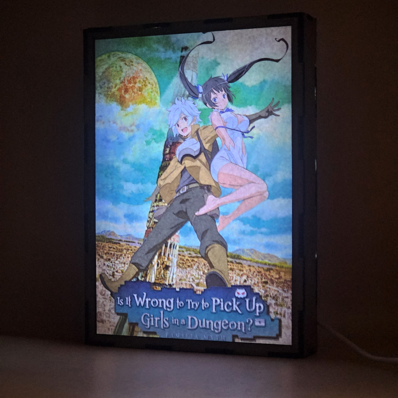 Lámpara ánime/manga  DanMachi  con doble imagen de la pareja Bell Cranel y Hestia, vista encendida, donde se revela la ilustración completa al encender la luz LED.