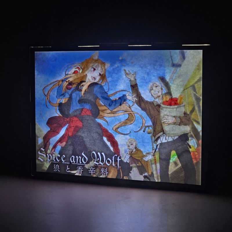 Lámpara ánime/manga  Spice and Wolf  con doble imagen del grupo Holo, Kraft Lawrence y Elsa Schieri, vista encendida, donde se revela la ilustración completa al encender la luz LED.